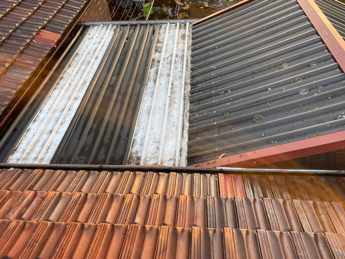Gutter between a tiled roof and a metal roof, packed with leaves and sticks before cleaning and clear afterwards - after