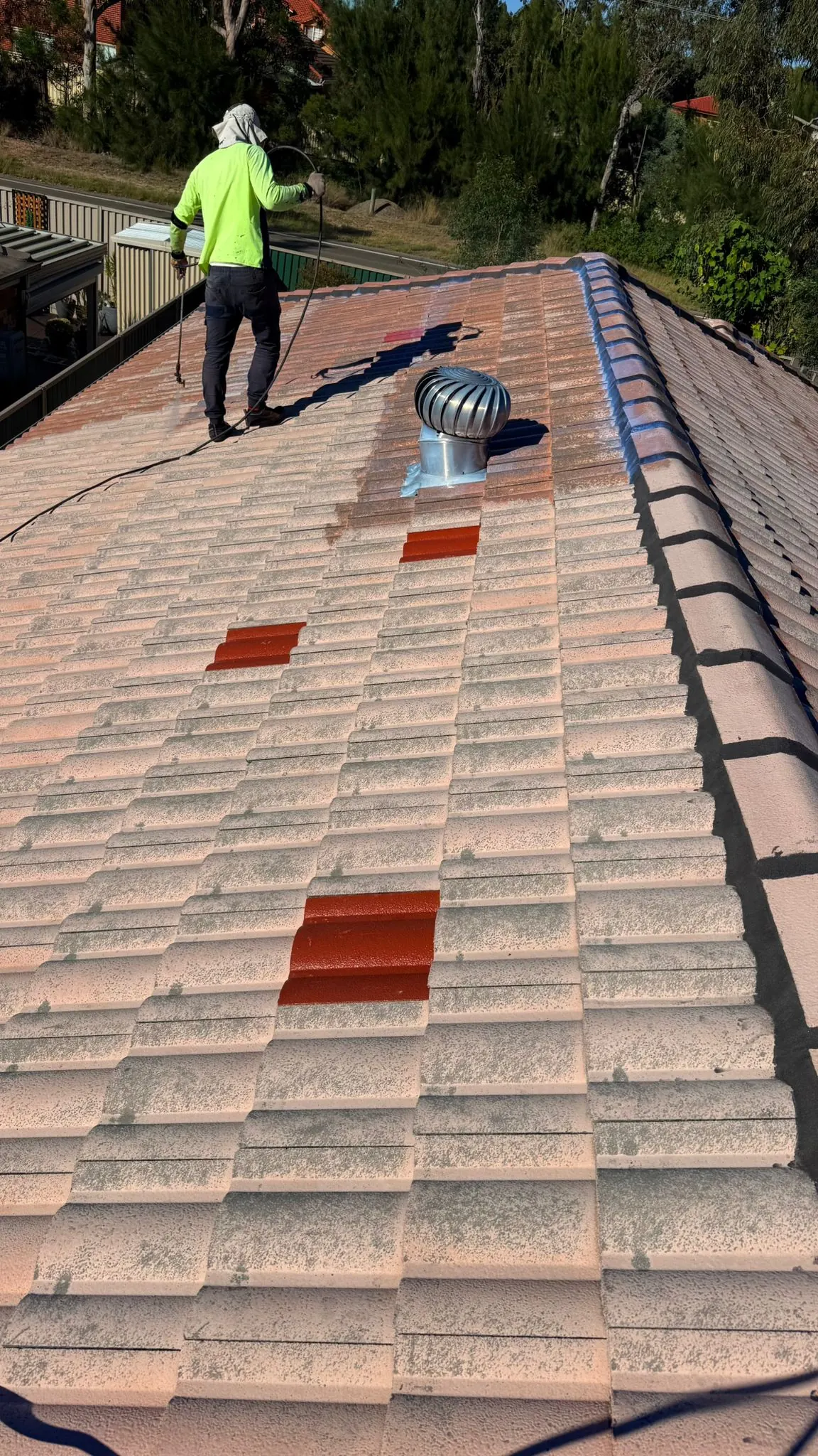 Roofing professional pressure cleaning a tiled roof